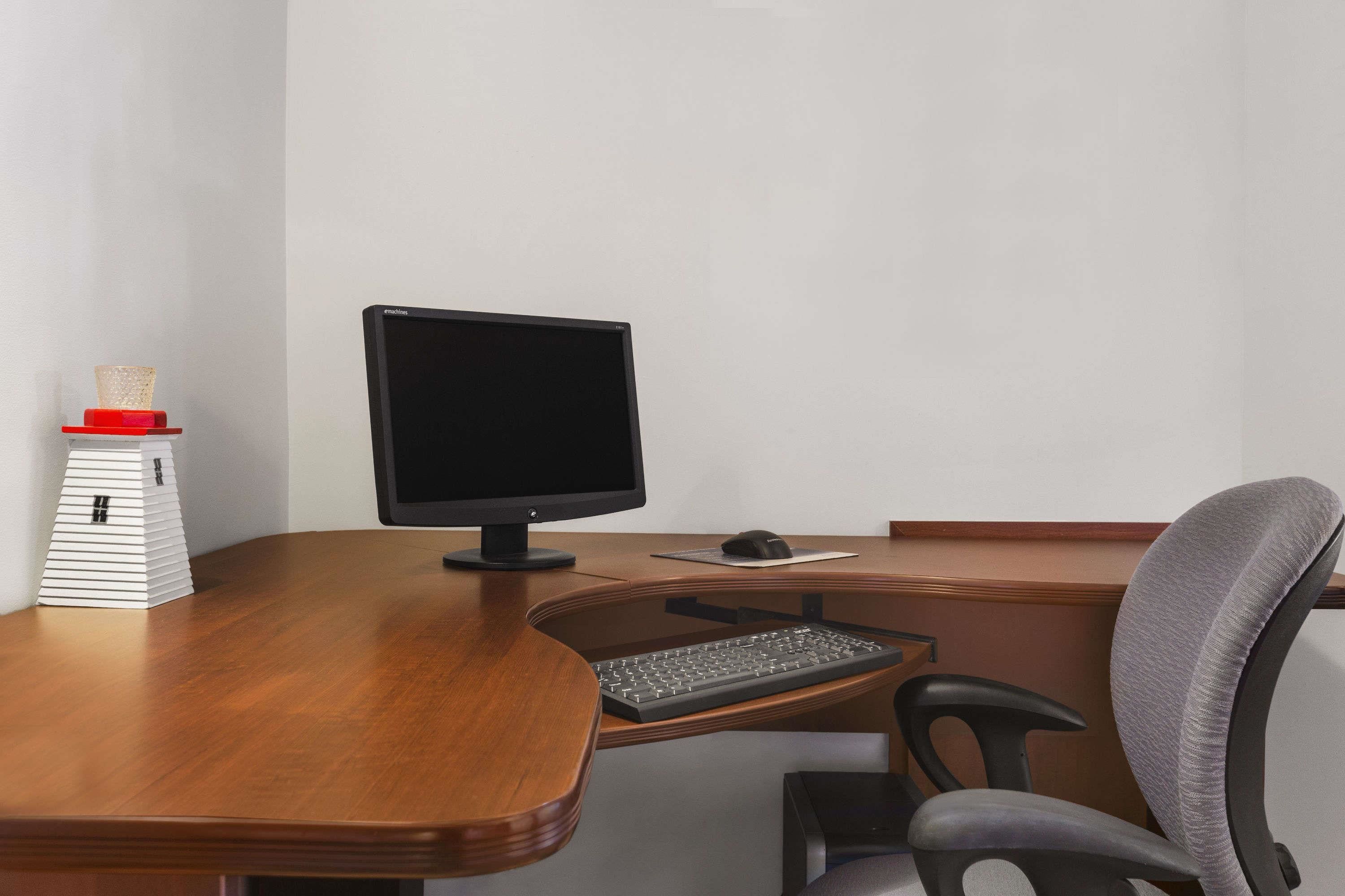A wooden desk with a computer monitor, keyboard, and mouse.