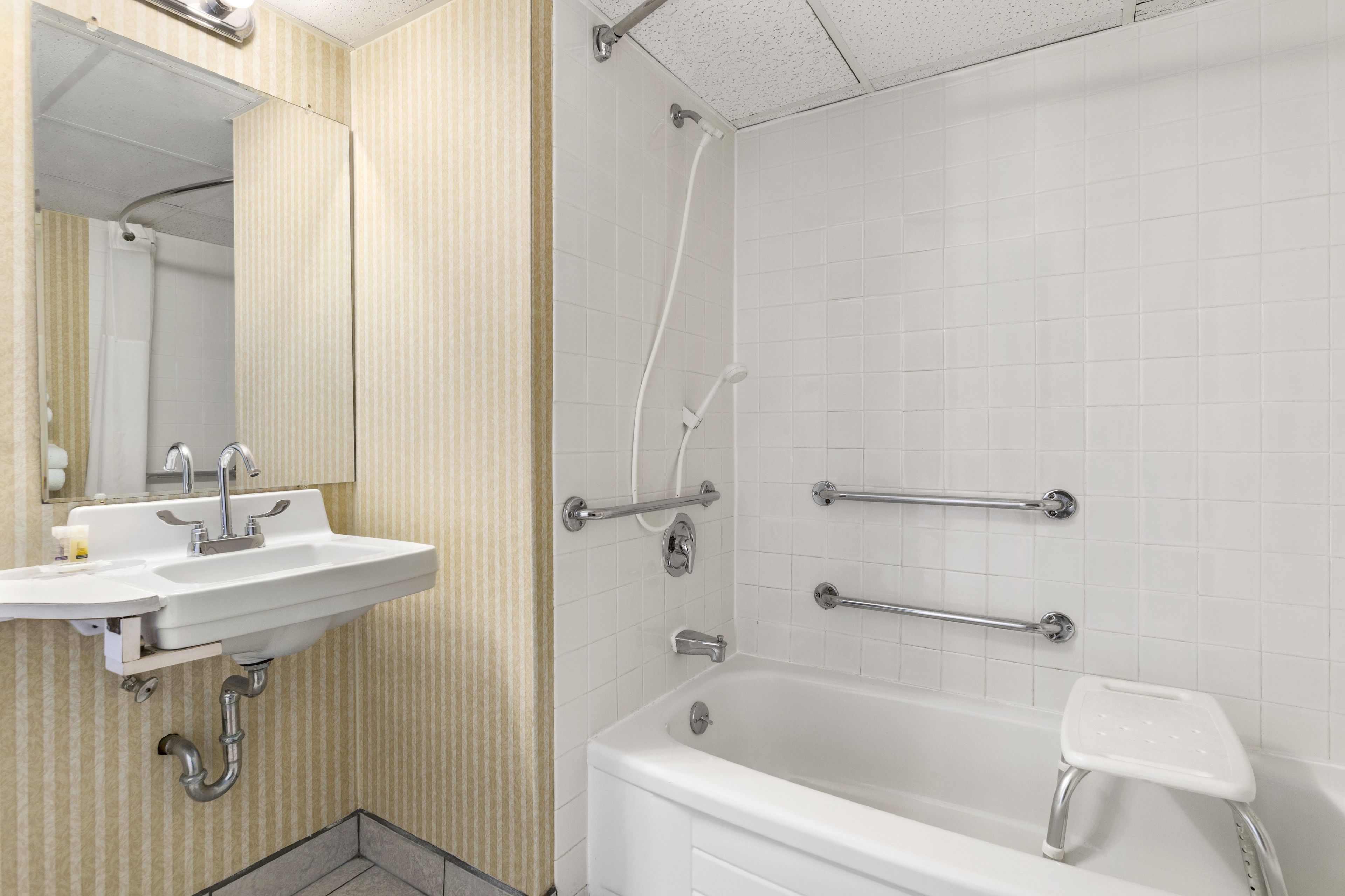 A bathroom with a white sink, mirror, and bathtub.