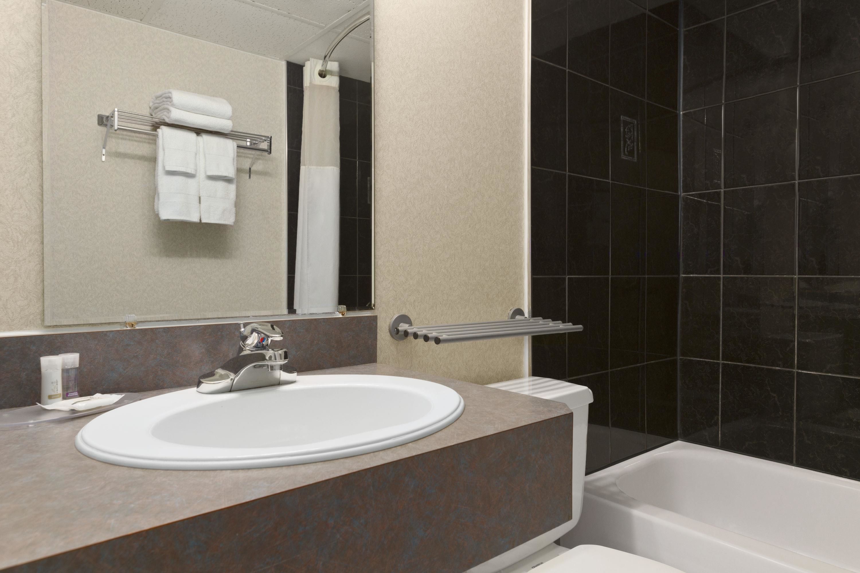 A modern bathroom with a white sink, a mirror, and a bathtub.