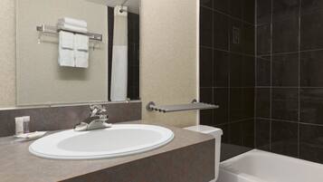 A modern bathroom with a white sink, a mirror, and a bathtub.
