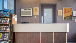 A reception desk with a check-in/out sign, a door, and a window.