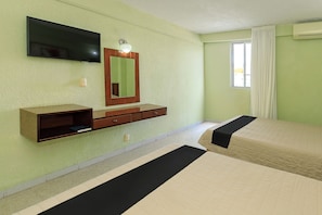 A hotel room with a bed, a TV mounted on the wall, a bedside table, and a window with curtains. - Palette Hotel Batab (Cancun)
