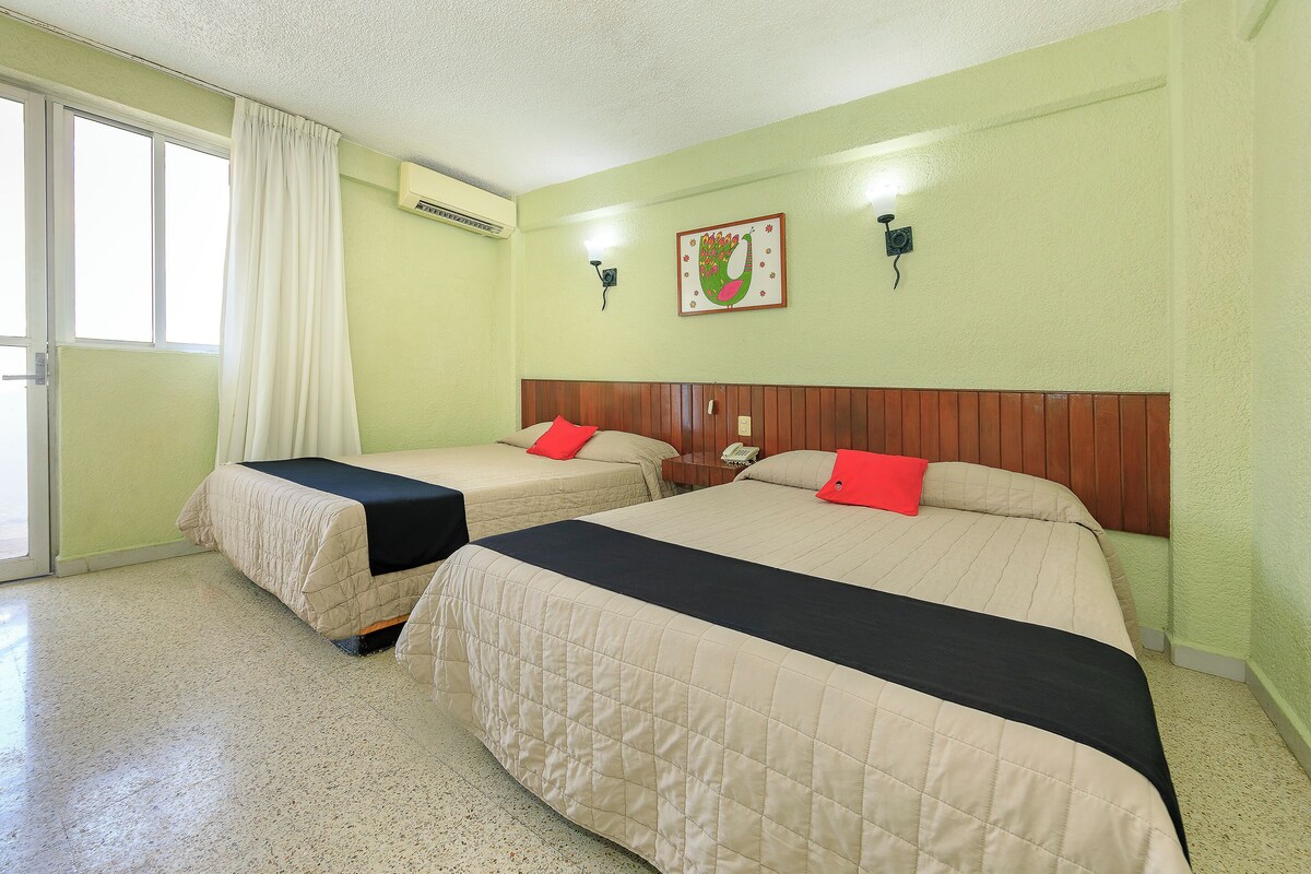 A hotel room with two beds, a window with curtains, an air conditioning unit, a wall-mounted telephone, and a decorative wall piece.