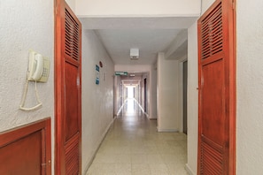 A corridor with wooden doors, a telephone, and directional signs. - Palette Hotel Batab (Cancun)
