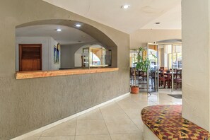 A hotel lobby with a reception desk, a clock, a plant, and a seating area. - Palette Hotel Batab (Cancun)