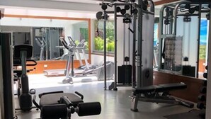 A gym with various exercise equipment, a mirrored wall, and a view of the outdoors. - Hotel Metropol (Mexico City)