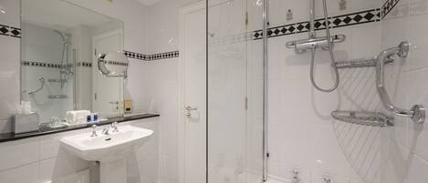 A modern bathroom with a glass-enclosed shower, a white sink, and a checkered floor.