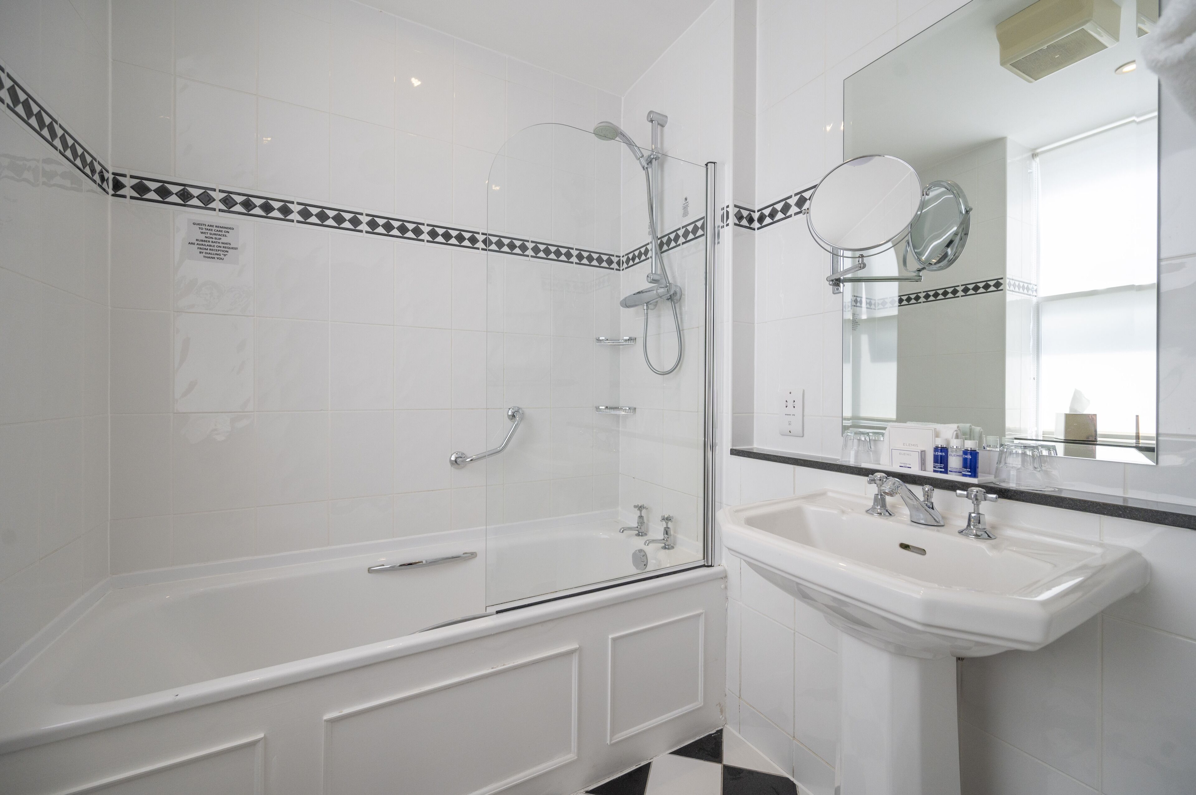 A modern bathroom with a glass-enclosed shower, a white bathtub, and a sink with a mirror above it.