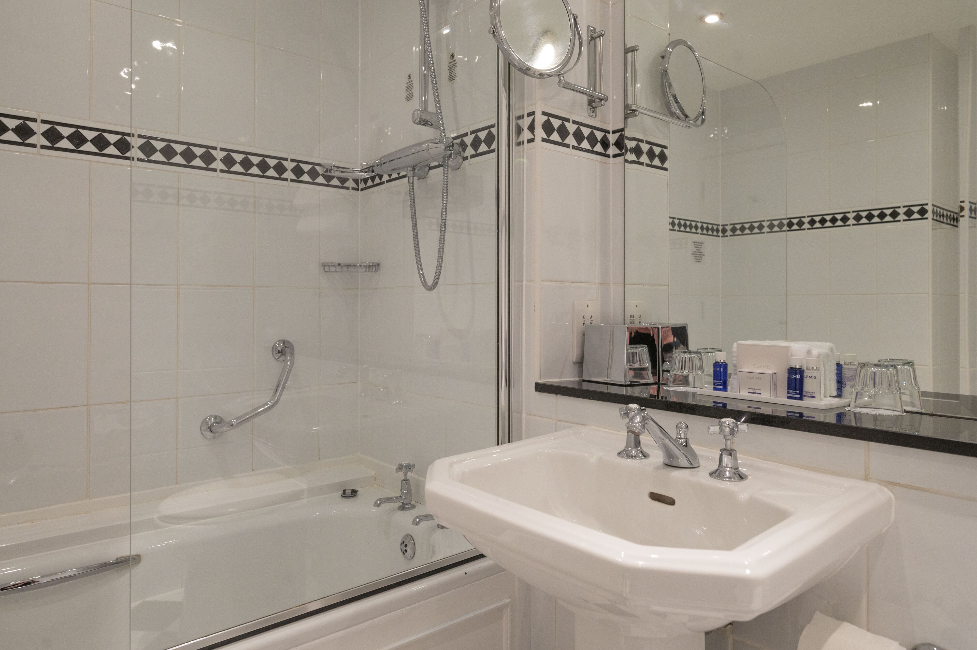 Ein modernes Badezimmer mit einer gläsernen Badewanne, einem weißen Waschbecken und einem großen Spiegel.