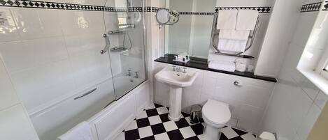A bathroom with a black and white checkered floor, a glass-enclosed shower, a white sink, and a toilet.