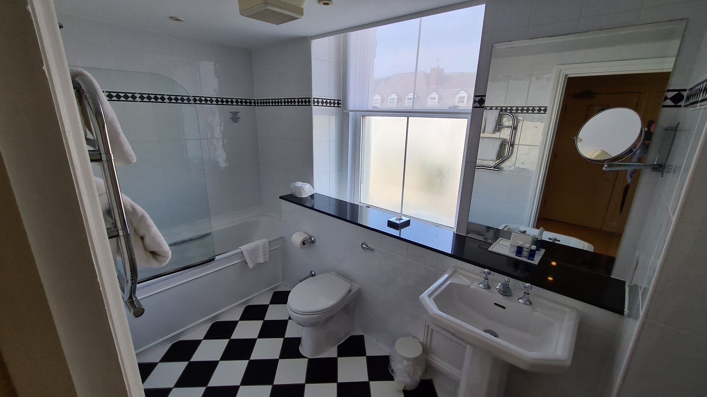 A bathroom with a black and white checkered floor, a toilet, a sink, and a shower area.