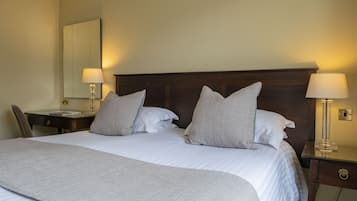 A neatly made bed with a wooden headboard, two bedside lamps, and a chair.