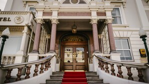 A grand entrance with a red carpet leading to a double door, flanked by columns and a staircase. - St George's Hotel (Llandudno)