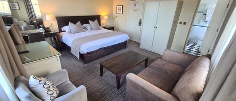 Quarto de hotel com cama, sofá, escrivaninha e cadeira.