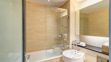 A modern bathroom with a glass-enclosed shower, a white sink, and a large mirror.