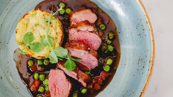 A plate with sliced meat, peas, and a potato.