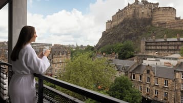 A person on a balcony overlooking a historic castle and cityscape.