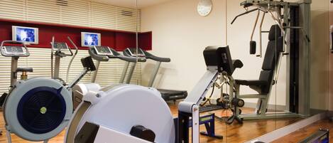 A gym with cardio machines, a weight bench, and a mirror.