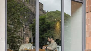 Un restaurante con amplios ventanales, un letrero que dice 'METRO BAR & BRASSERIE', y reflejos de personas en el interior.