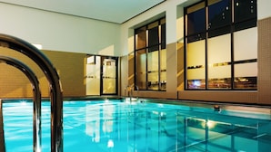 A swimming pool with clear water, surrounded by tiled walls and large windows.