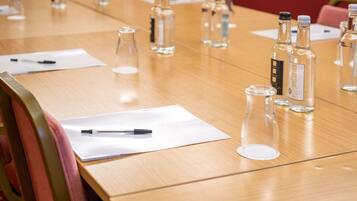Una mesa de conferencias con botellas de vidrio transparente, bolígrafos y documentos.