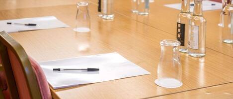 A conference table with clear glass bottles, pens, and papers.
