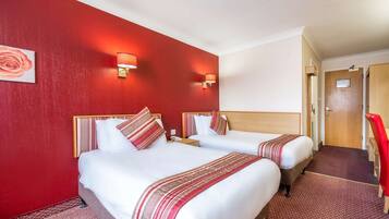 A hotel room with two beds, red walls, and a red carpet.