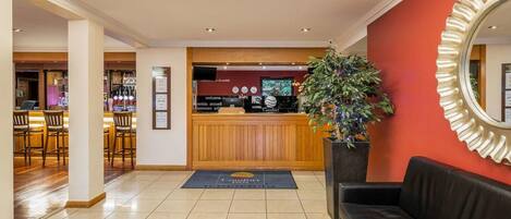 A hotel lobby with a reception desk, a bar area, and a seating area.