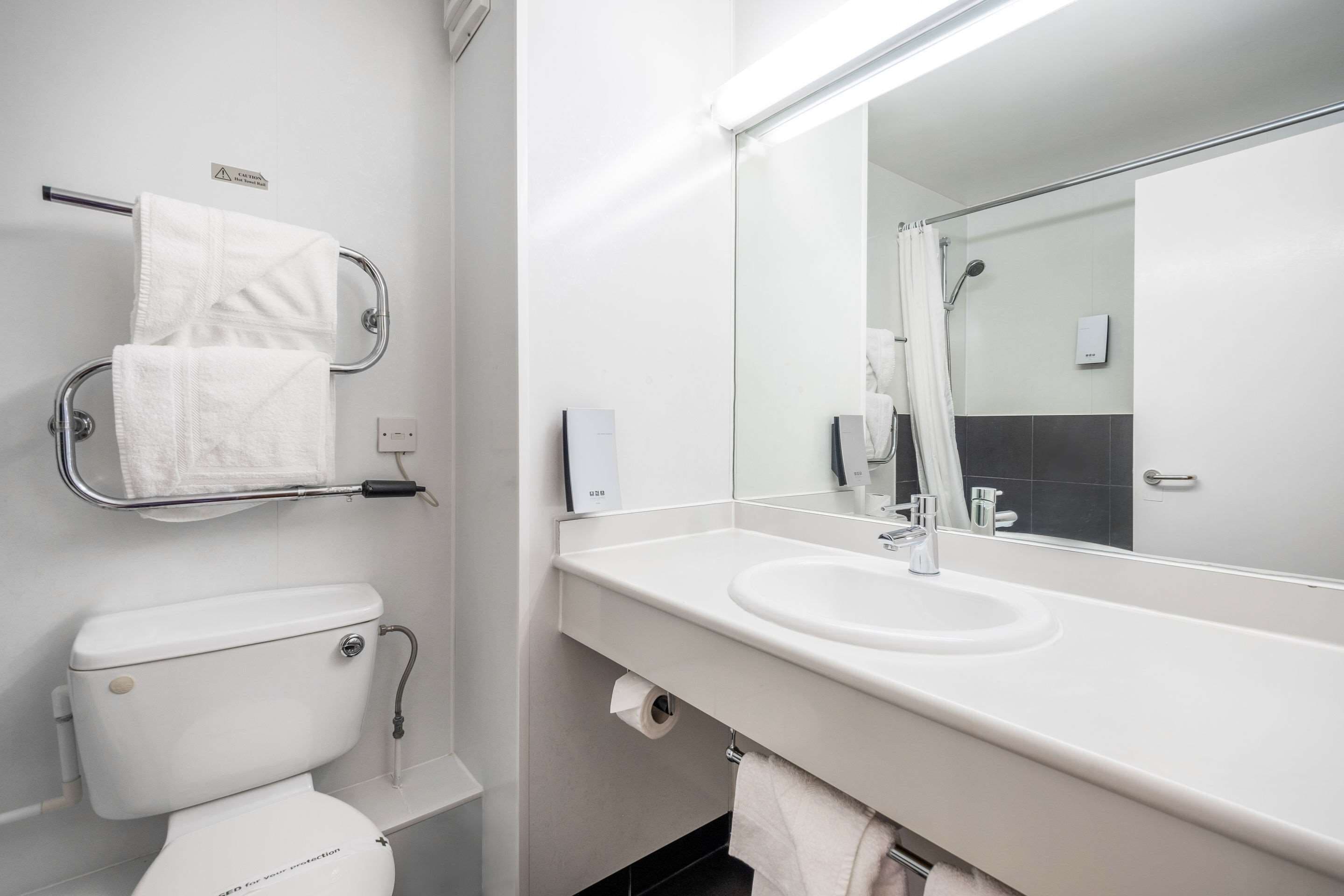 A modern bathroom with a white toilet, a sink, and a large mirror.