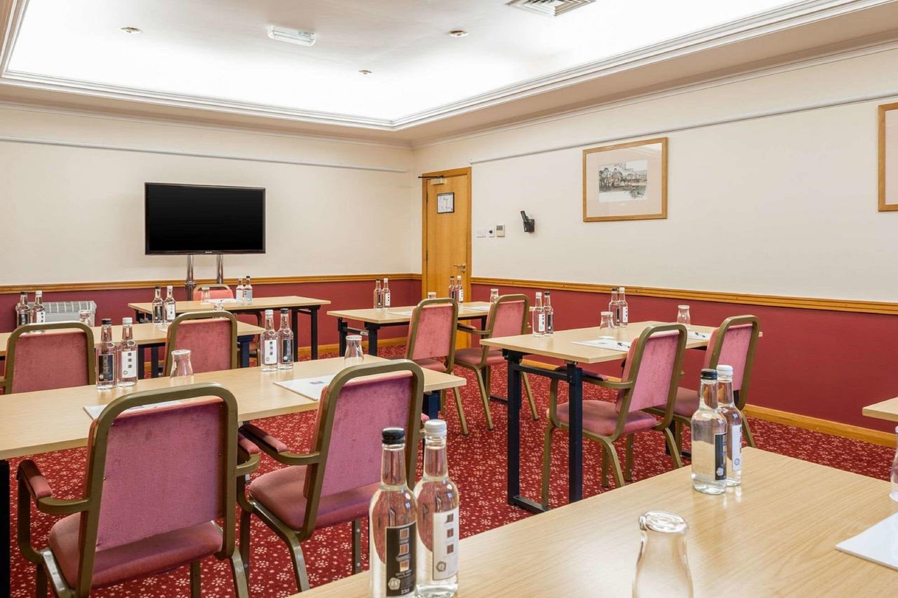 A conference room with tables, chairs, and a television.