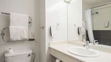Un baño moderno con inodoro, lavamanos y espejo. Hay un perchero con dos toallas, un dispensador de toallas de papel y un dispensador de jabón.