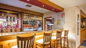 Uma área de bar com cadeiras de madeira e um balcão exibindo diversos tipos de garrafas.