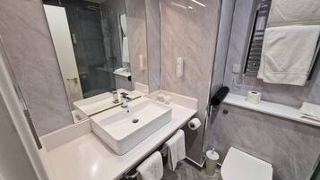 Un baño moderno con un espejo grande, un lavabo blanco y un inodoro.