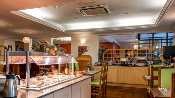 Um balcão de café da manhã com máquina de café, uma cesta de frutas e um buffet.