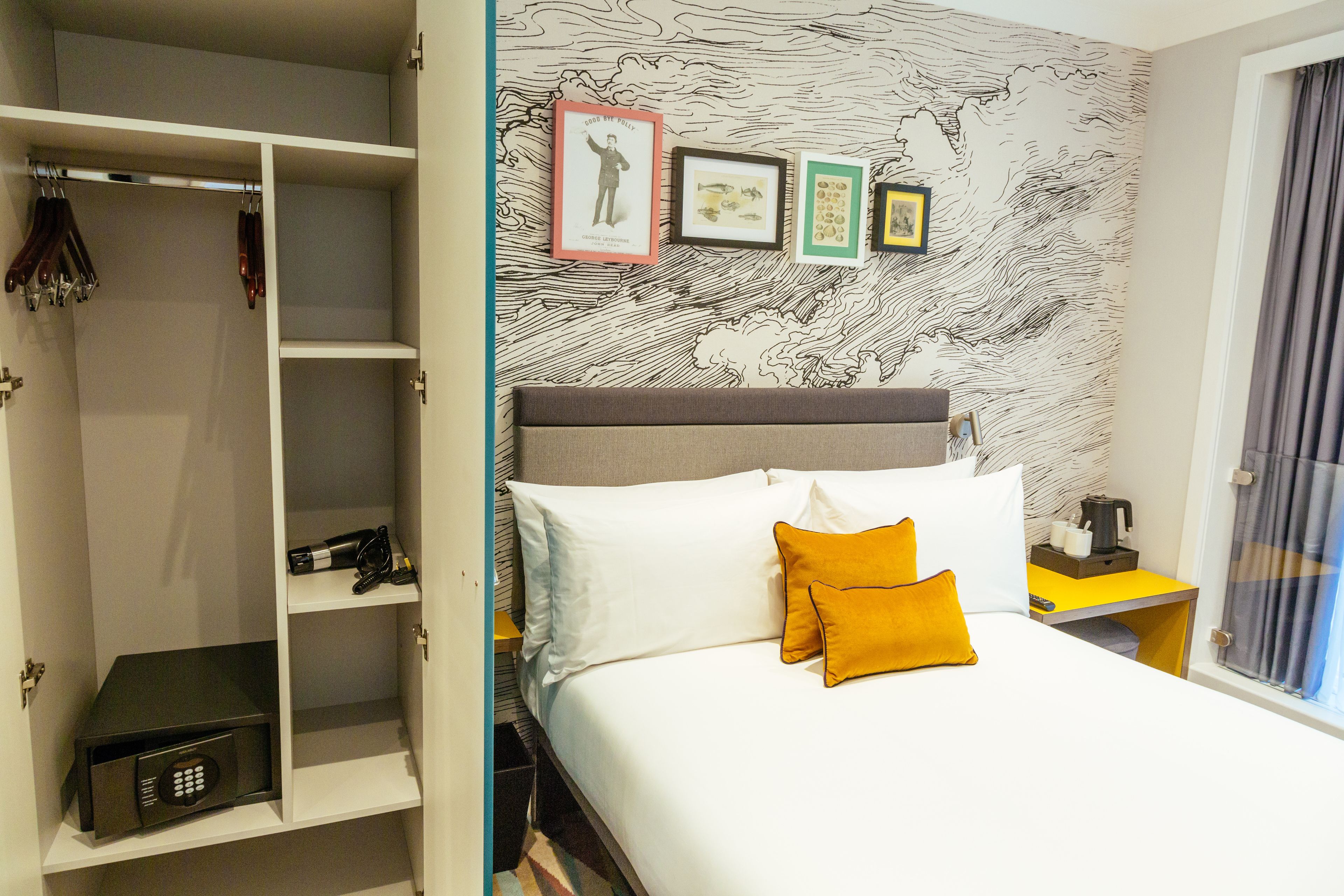 Una habitación de hotel con una cama, un armario y una pared con cuadros.