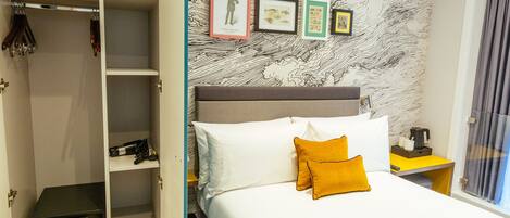 Una habitación de hotel con una cama, un armario y una pared con cuadros.