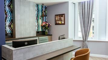 A modern reception desk with a HP logo, a patterned wall, a vase of flowers, and a framed picture on the wall.