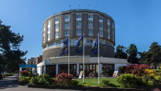 A hotel with a circular facade, multiple flags, and a reception area. - Roundhouse Hotel Bournemouth (Bournemouth)