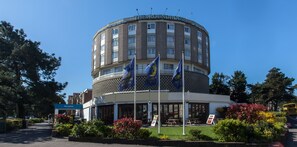 A hotel with a circular facade, multiple flags, and a reception area. - Roundhouse Hotel Bournemouth (Bournemouth)