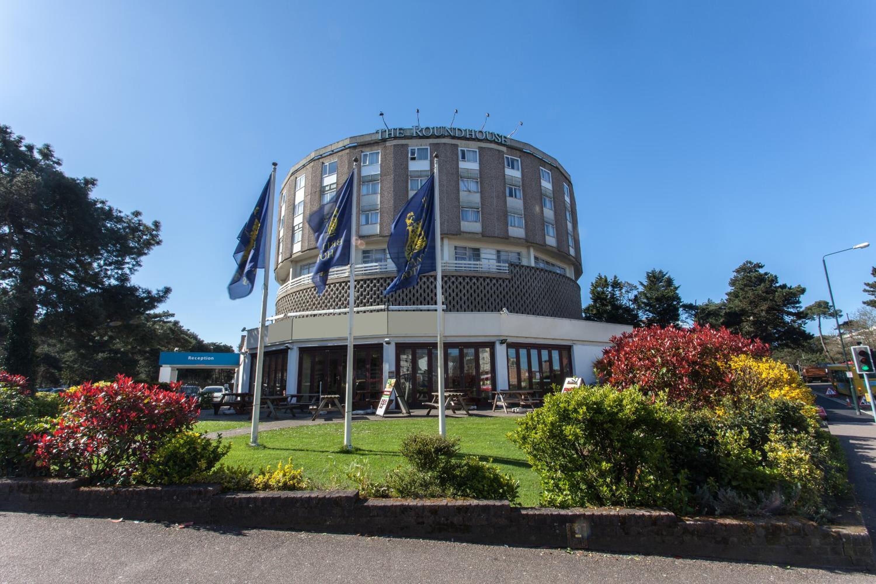 A round building with multiple flags, a reception area, and a landscaped garden.