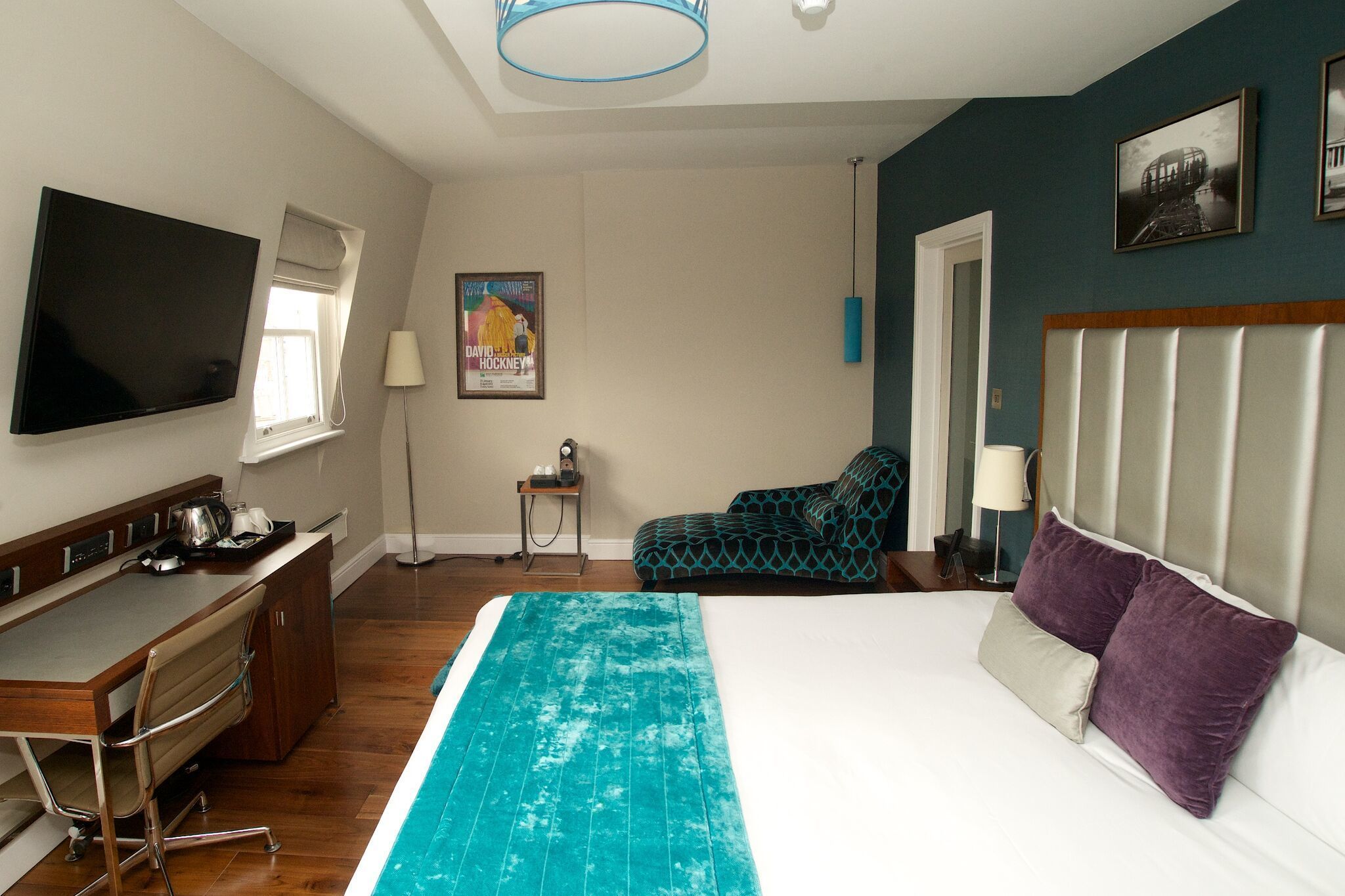 Ein Hotelzimmer mit einem Bett, einem Schreibtisch, einem Sessel, einem Fernseher und einem Fenster.
