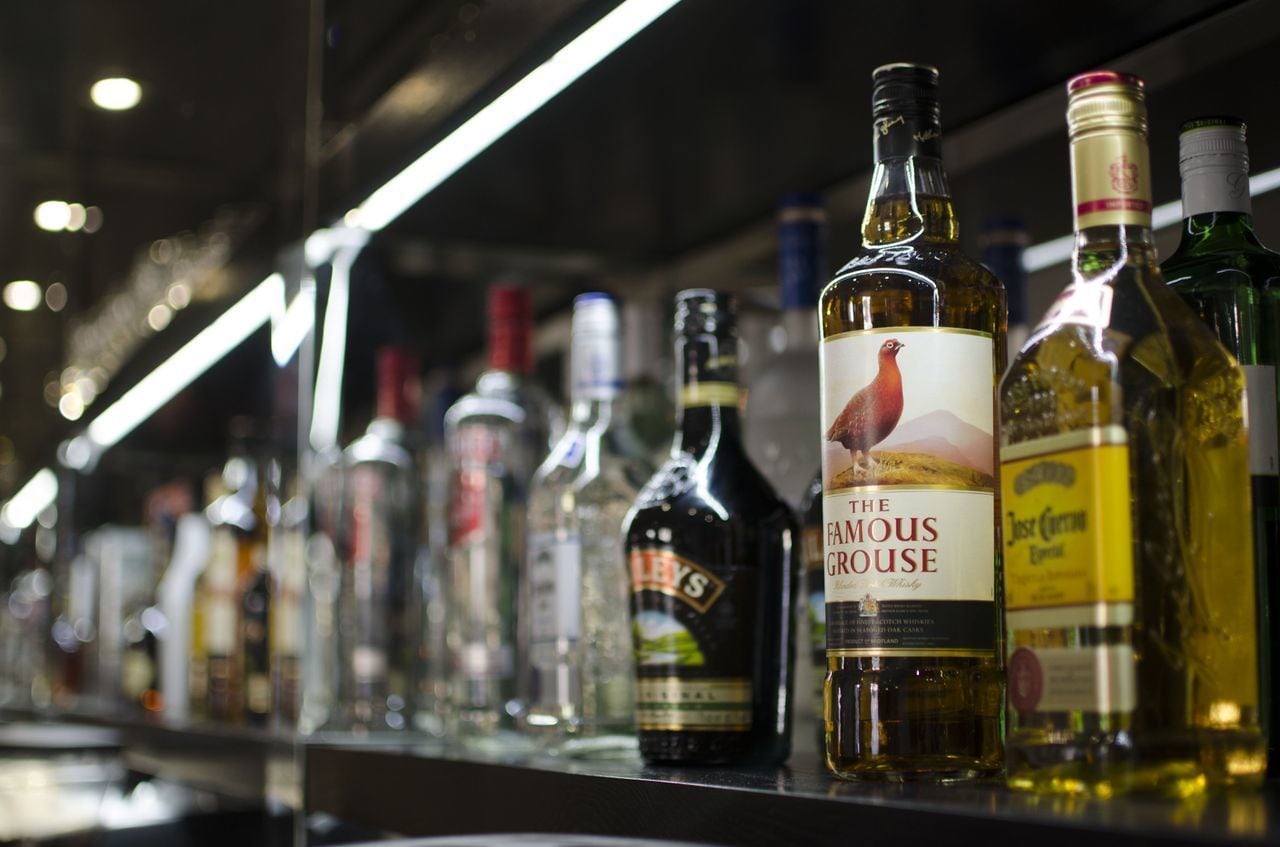 A bar with various bottles of alcohol, including a prominent bottle labeled "The Famous Grouse."