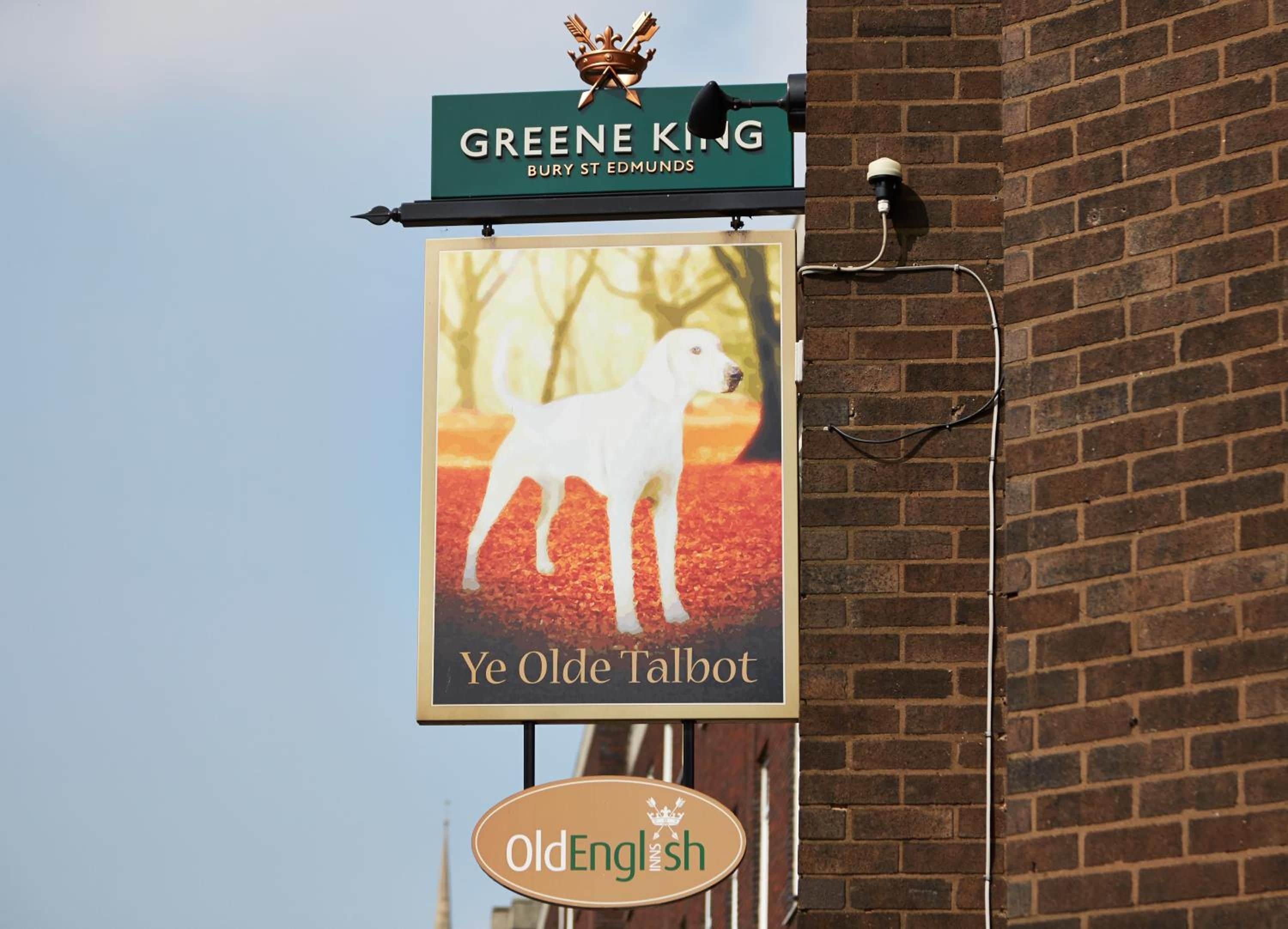 A sign for Greene King Bury St Edmunds with a picture of a white dog and the text 'Ye Olde Talbot.'