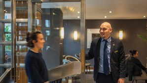 A modern hotel lobby with a reception desk, seating area, and a glass partition. - Tavistock Hotel (London)