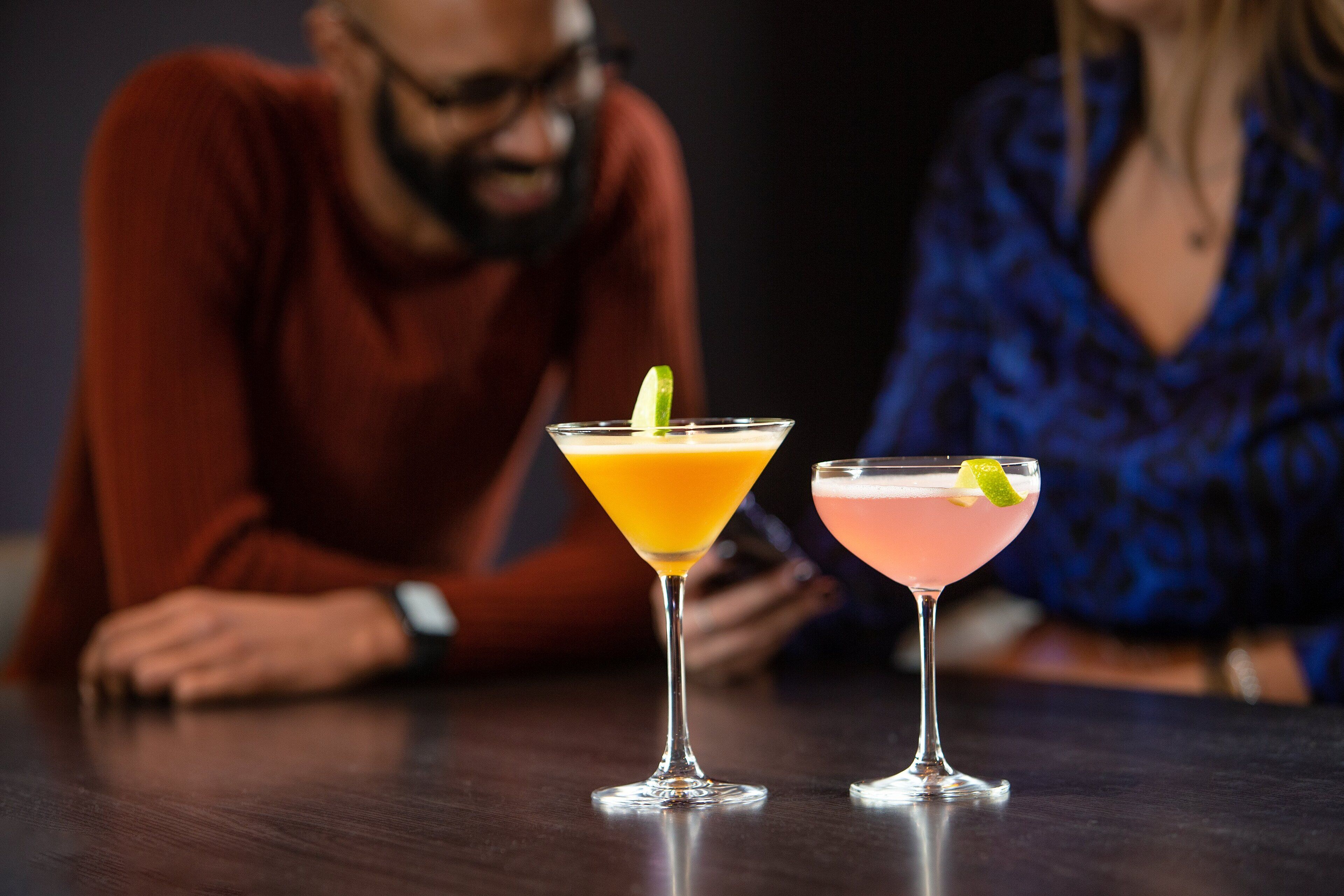 Kaksi cocktail-drinkkiä pöydällä, taustalla näkyy henkilö.