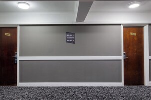 Ein Hotelzimmer mit einer großen Schiebetür, einem Schild mit den Zimmernummern und einem Teppichboden.