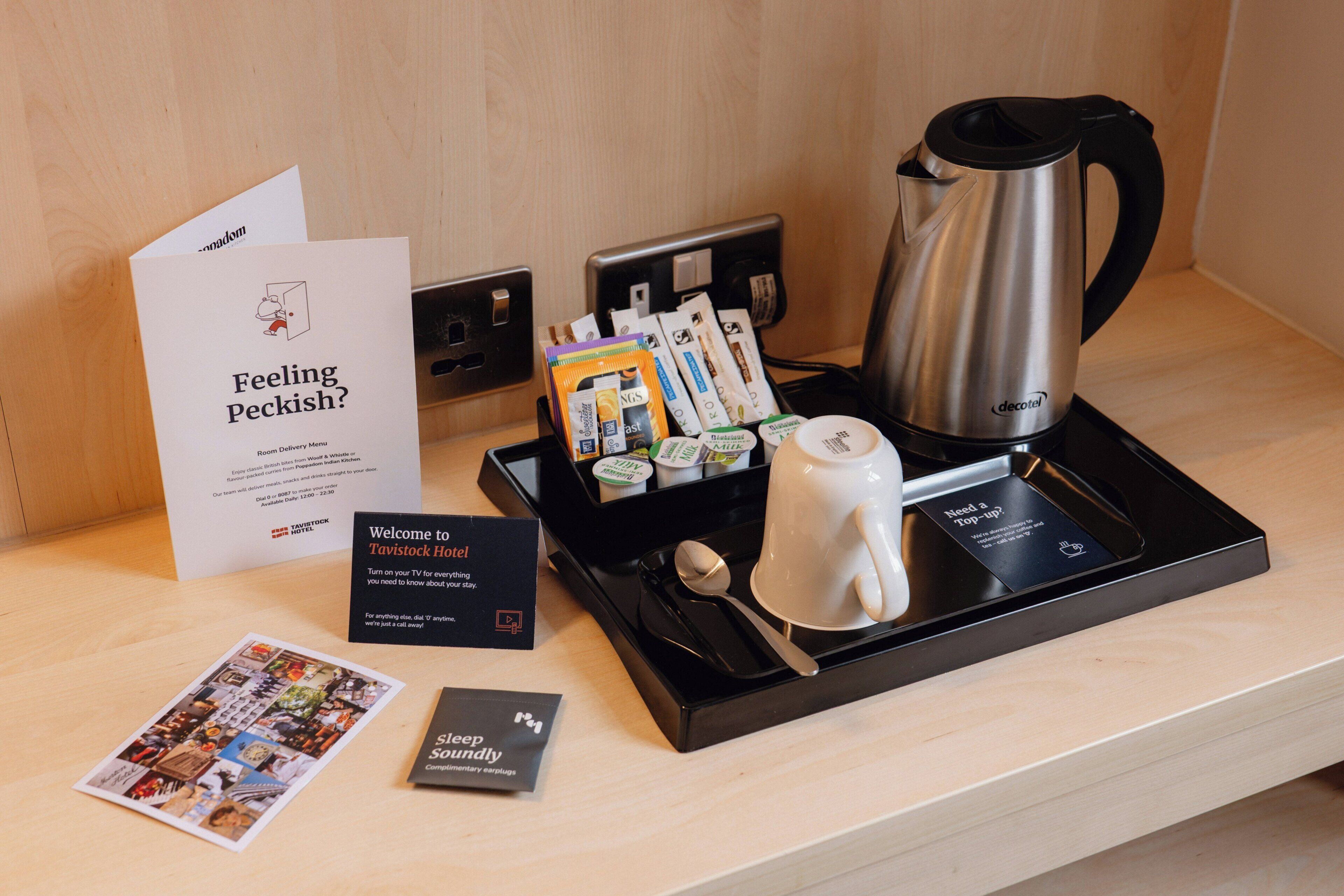 A hotel room's reception area with a tray containing a coffee maker, a mug, and various toiletries.