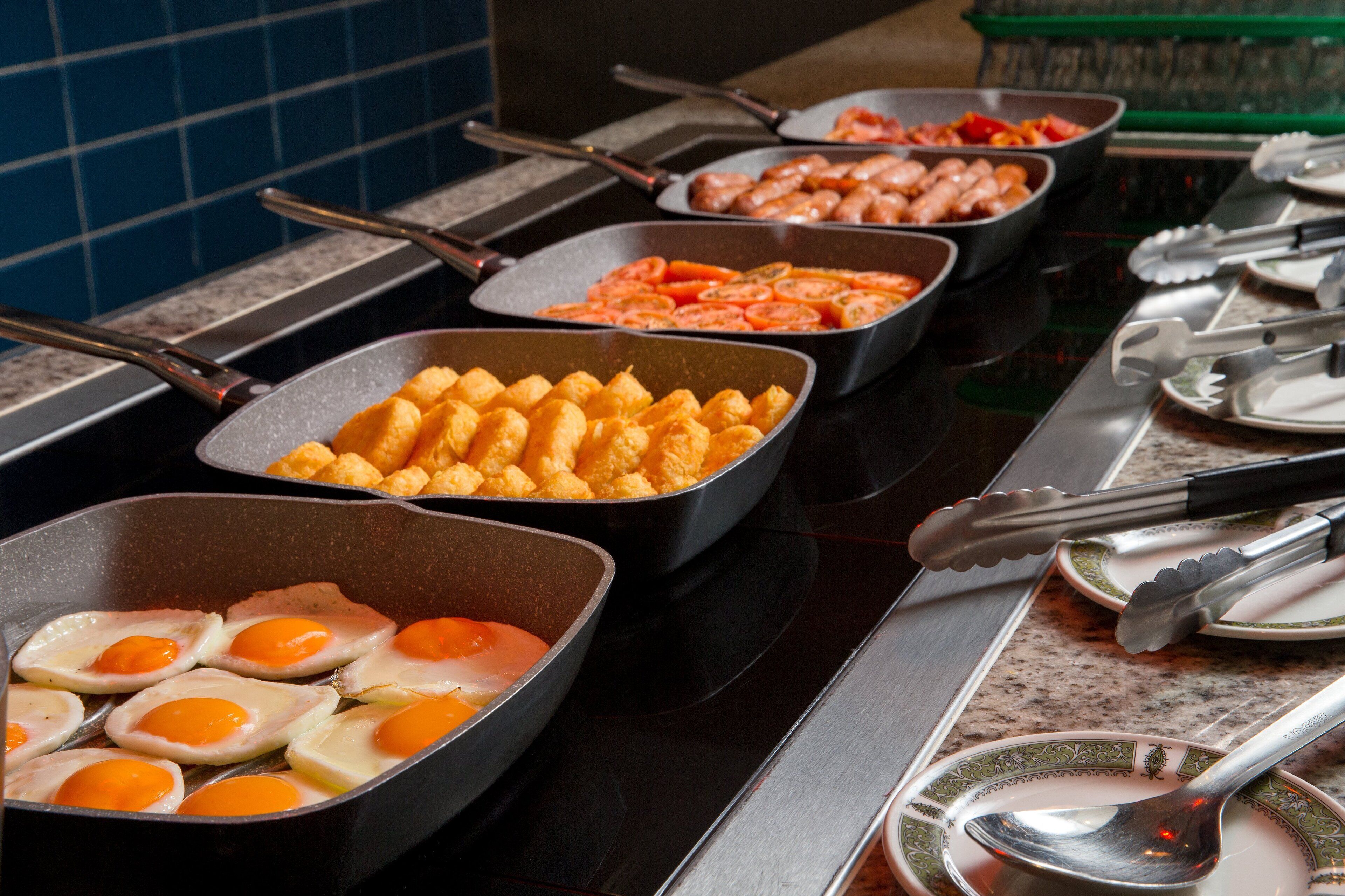 A buffet with various food items including eggs, shrimp, and tater tots.