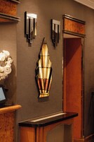 A reception area with a wooden counter, a wall-mounted light fixture, and a mirror.