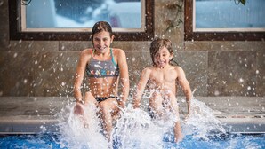 Dos niños jugando en una piscina con salpicaduras de agua.